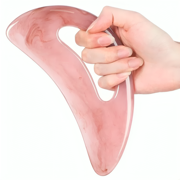 Rosa gua sha-skrapa i marmormönster som hålls i handen