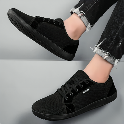 Svart minimalistisk barfotasko sedd från sidan och ovanifrån, buren med svarta jeans