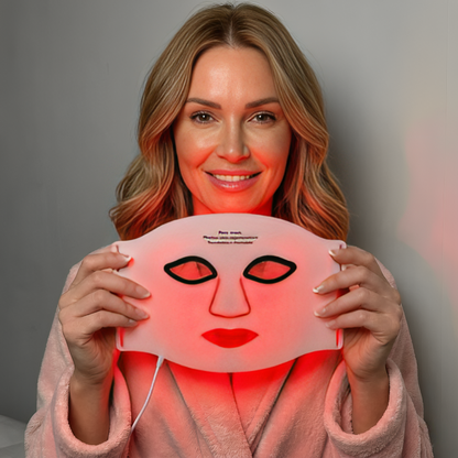 Kvinna håller upp InfraRelief™ Ansiktsmask 2.0 med aktivt rödljus – LED-mask i medicinskt silikon för hudvård hemma