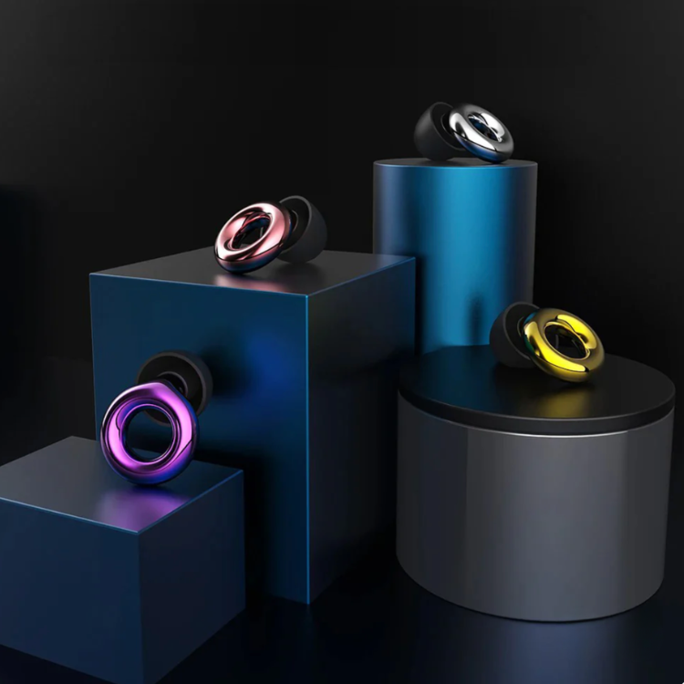 Fyra öronproppar i olika färger – lila, rosa, silver och guld – placerade på geometriska podier mot mörk bakgrund