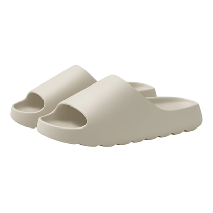 Slip-in tofflor i beige EVA-material med tjock mjuk sula och vågmönstrad undersida, mot vit bakgrund